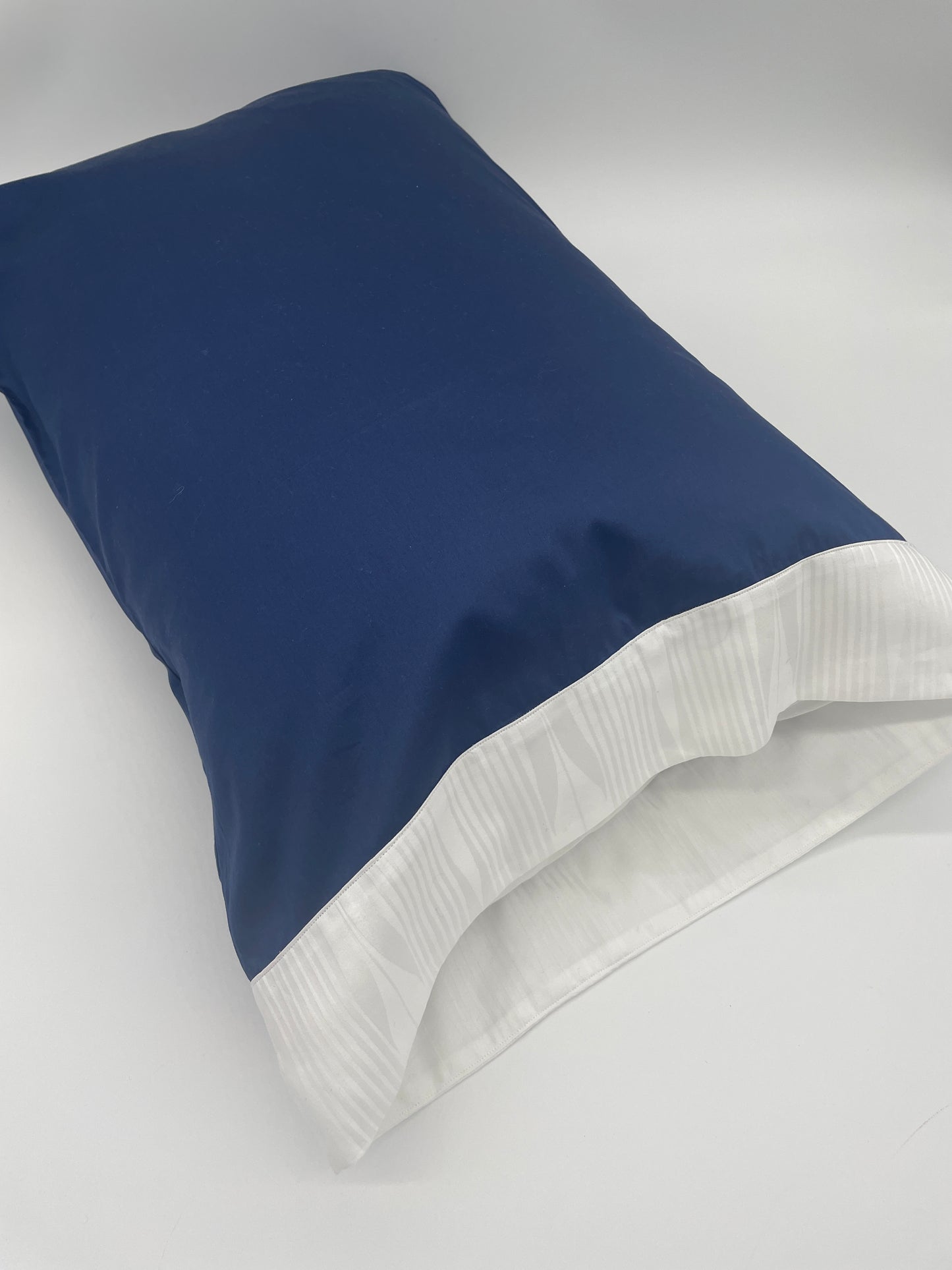 Kearsley Pillowcase on pillow.  Navy Soleil 300 thread count Sateen with a white on white Soleil jacquard border (Soleil is an abstracted sun ray jacquard border in white on white).  Made in Italy.  Fine linens.  Daily Essentials.