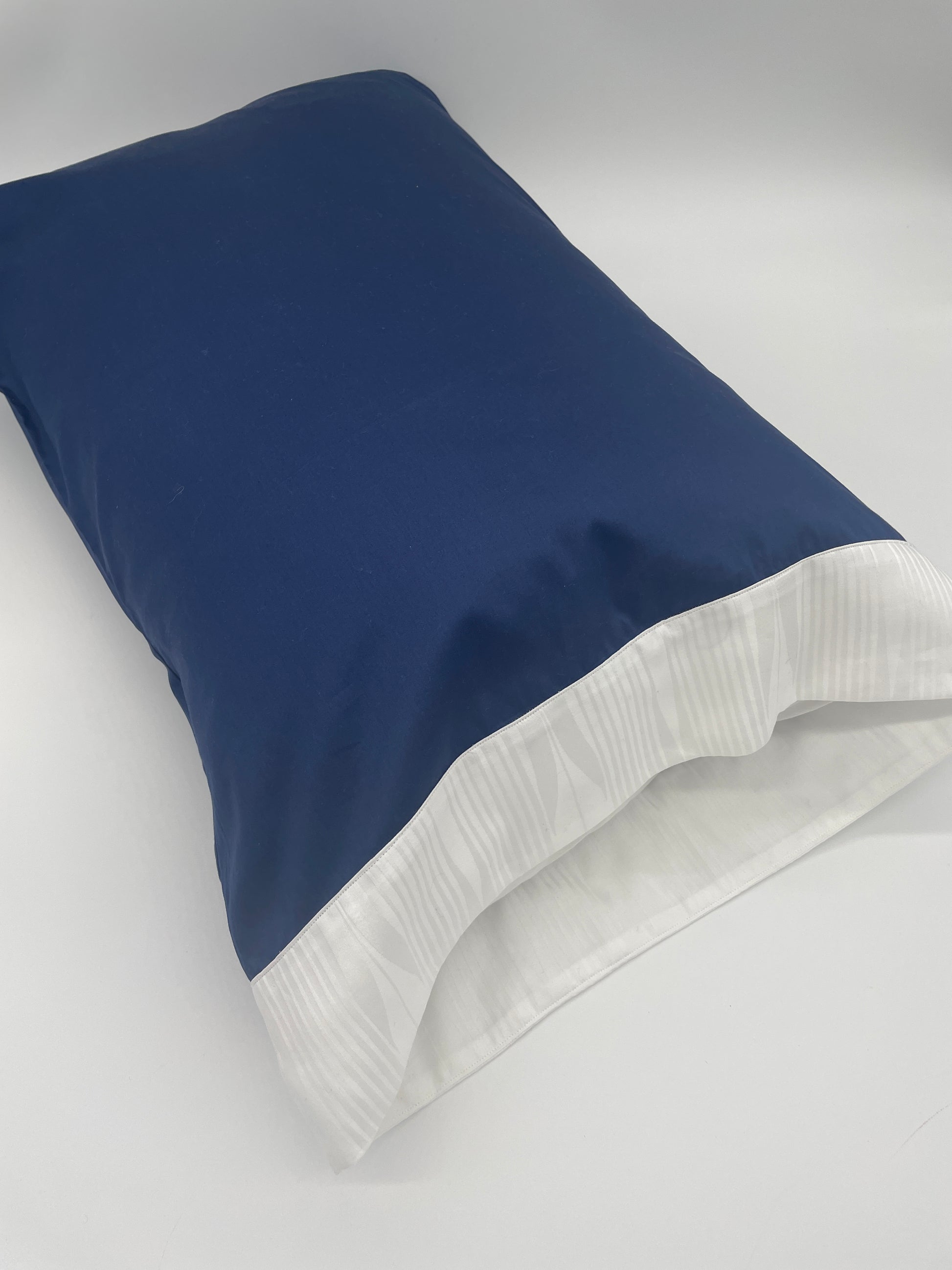 Kearsley Pillowcase on pillow.  Navy Soleil 300 thread count Sateen with a white on white Soleil jacquard border (Soleil is an abstracted sun ray jacquard border in white on white).  Made in Italy.  Fine linens.  Daily Essentials.